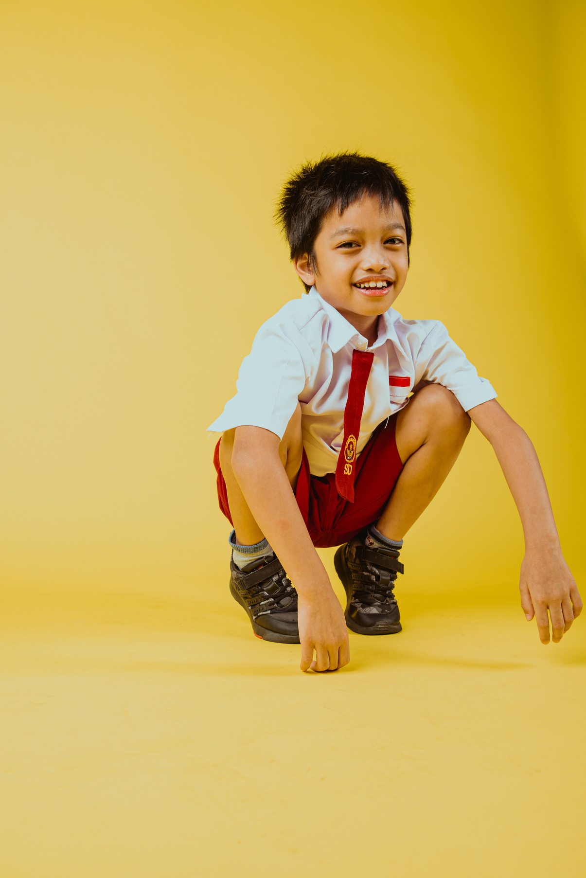 Portrait of a Schoolboy Sitting on Yellow Background